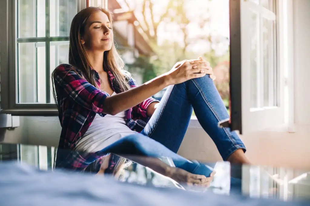 Beautiful young woman sitting at a windowsill having rest and fresh air, with copy space and country side view. Shot made during Istockalypse Paris 2016 event.