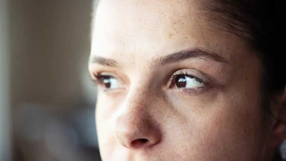 Extreme closeup of a freckled woman looking away.