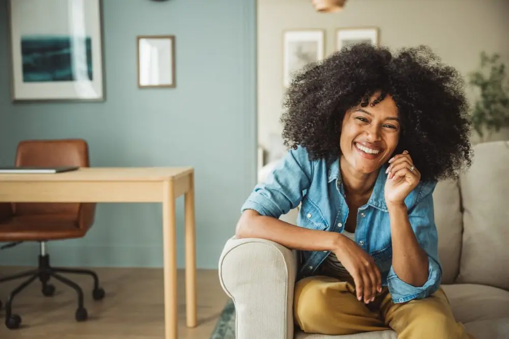 Shot of young happy woman sitting in comfortable and modern home.